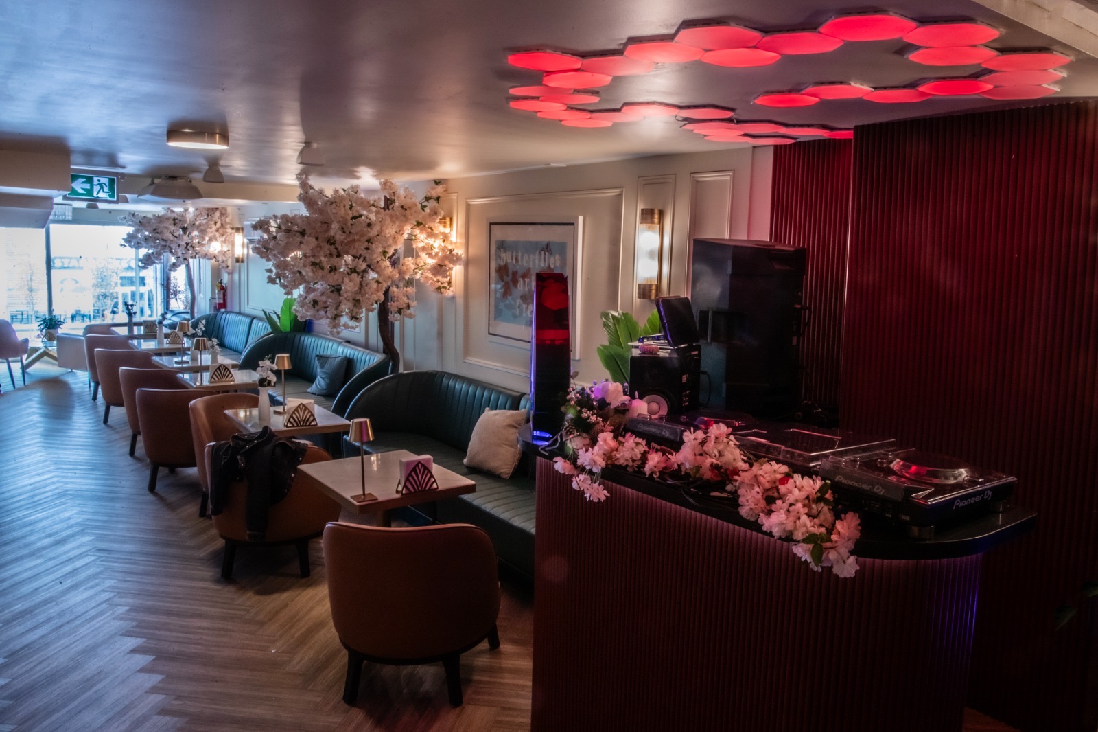 DJ booth framed by blossoms with red honeycomb ceiling lights at Yorkville Lounge