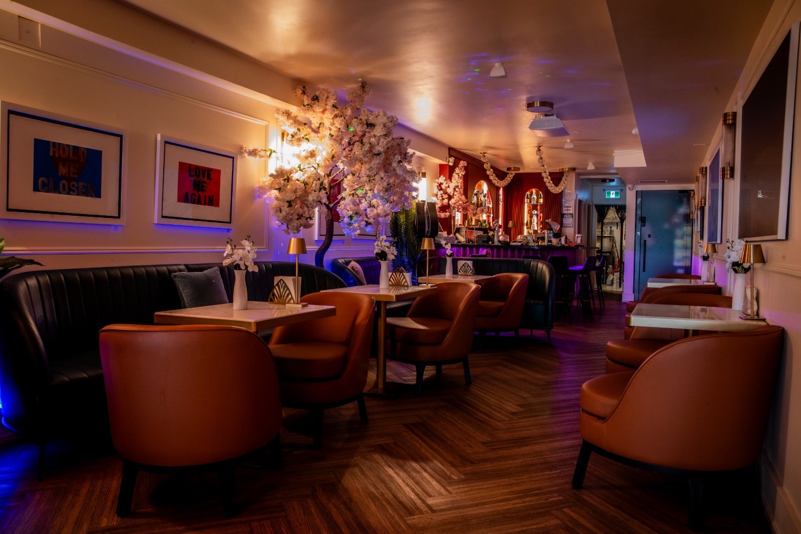 Lounge view toward the bar with Love Me Again pop-art prints and blossom tree
