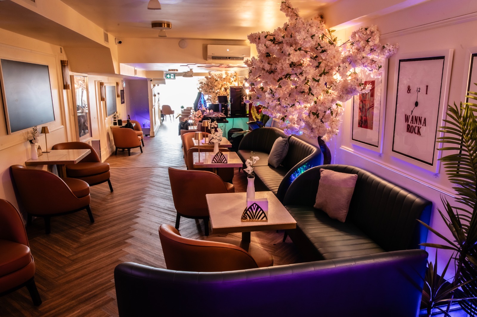 Lounge view with 'I Wanna Rock' pop-art and blossom tree under purple lighting